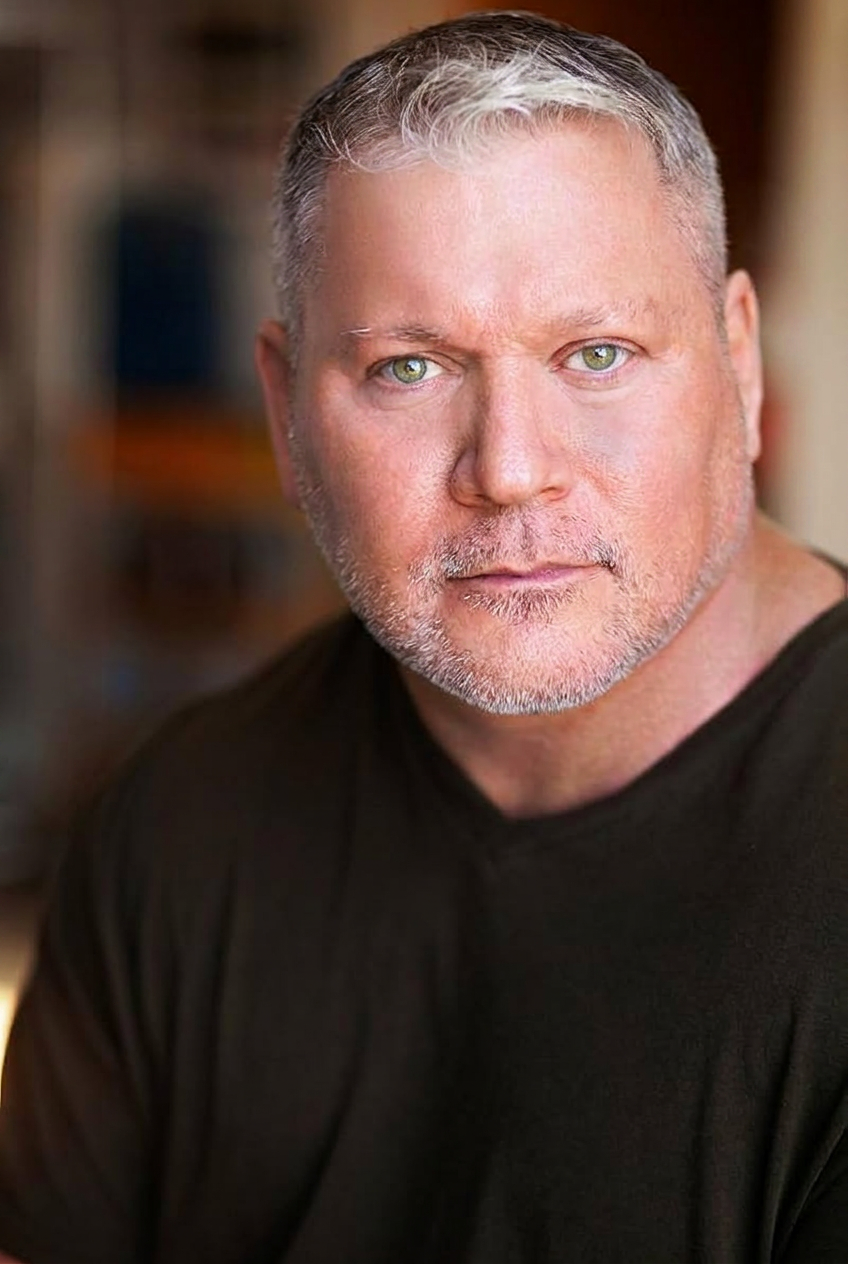 Benjamin Poe in a close-up dramatic headshot with direct eye contact to camera